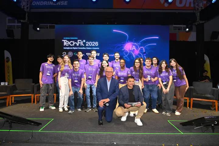 Equipe de staff da TechFil 2026, de camisetas roxas, reunida no palco